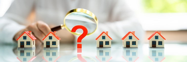 Magnifying glass and question mark hovering over a row of miniature houses