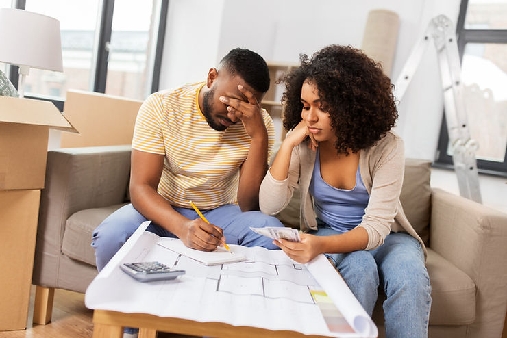 Stressed couple adding up repair costs over a floor plan with a calculator
